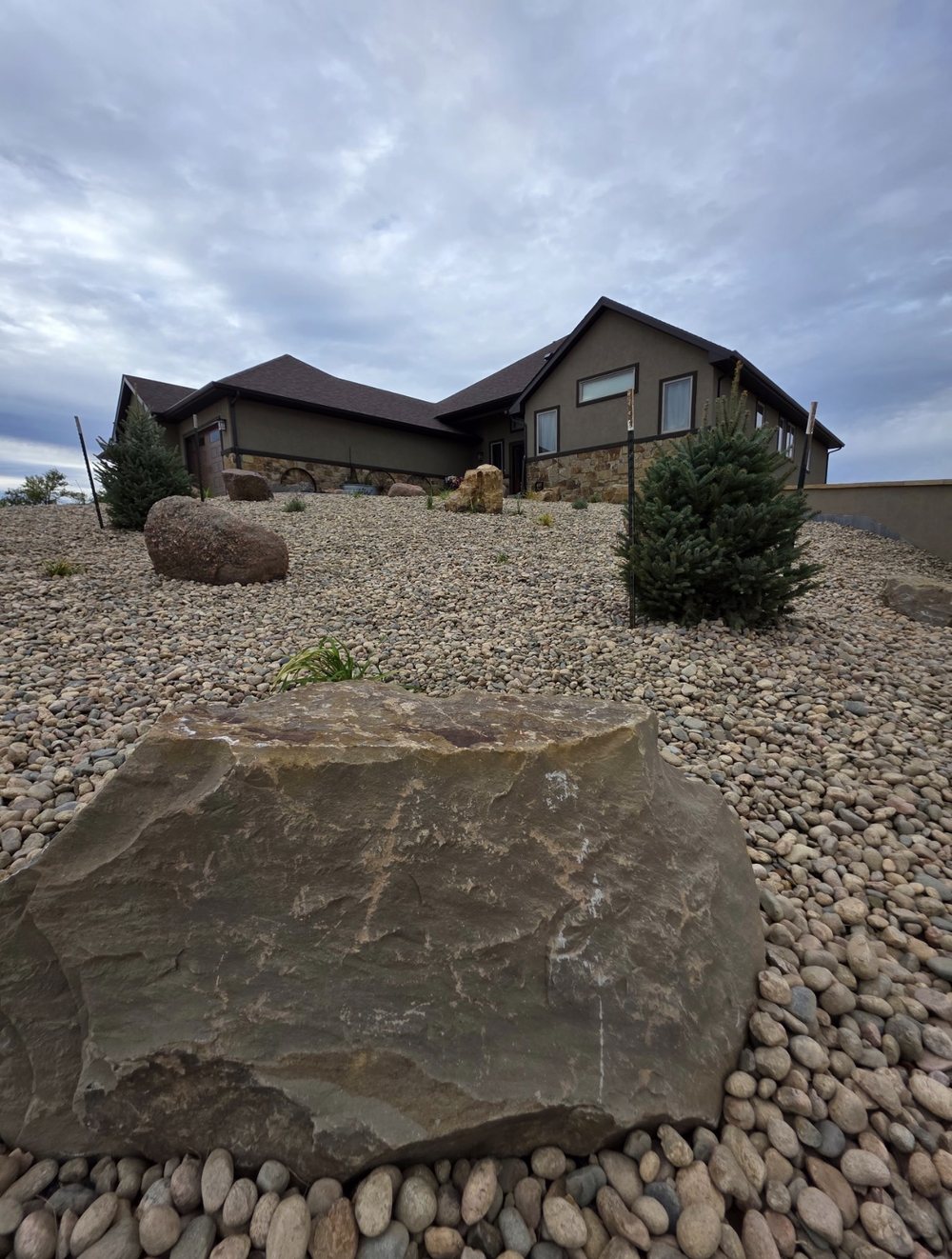 Boulder and river rock landscaping bed with spruce trees, Cheyenne, Wyoming