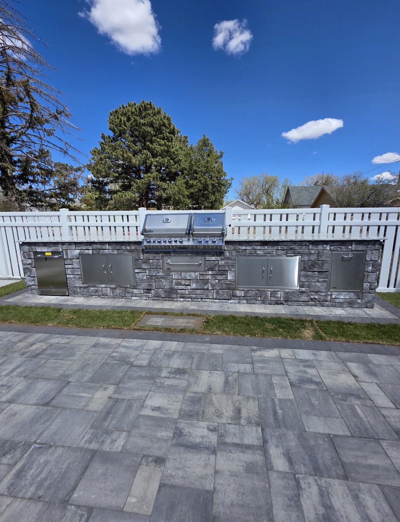 Stone-veneer outdoor kitchen island with built-in grill, refrigerator, storage doors and granite countertop, Cheyenne, Wyoming